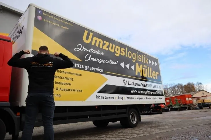 umzugshelfer steht vor umzugswagen auf betriebshof